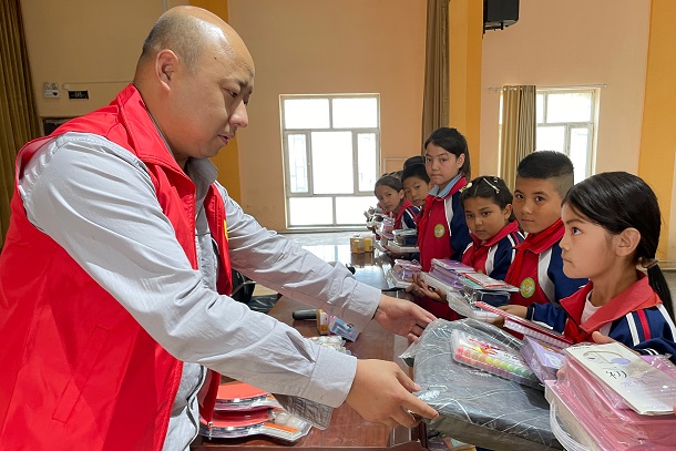 圖為張成國給學(xué)生贈(zèng)送文具